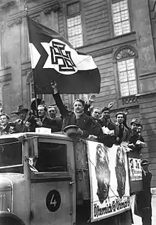 Photographie en noir et blanc d'hommes à bord d'un camion et arborant un drapeau