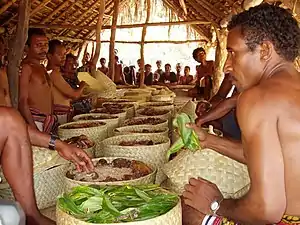 Il s'agit de l'offrande appelée Iluwai Malu bu (le crachat et la noix de bétel). Le crachat symbolise la bénédiction des ancêtres et de la terre. Malu bu : le reste de la noix de bétel des ancêtres. Chaque membre du village reçoit sa part. Ceux qui vivent à l'étranger comptent également.