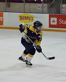 Photographie d'une joueuse de hockey avec un maillot noir, jaune et blanc