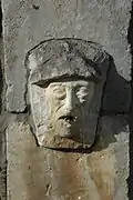 Photographie d'une fontaine représentant un visage d’homme surmonté d’un béret basque.