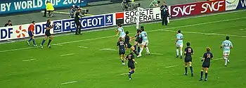 Plan large de joueurs de rugby en action sur un terrain.