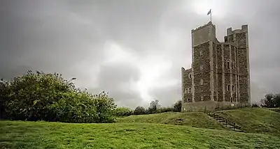 A grey stone tower surrounded by uneven ground.