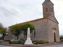 Une église en pierre à clocher carré au-dessus du porche à fronton classique.