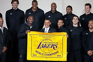Onze hommes noirs debout derrière un drapeau jaune avec l'inscription Lakers World Champion.