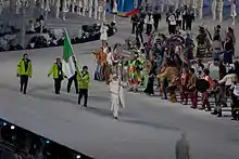 3 personnes en vert défilant derrière une autre vêtue de blanc et portant un panneau où il est inscrit Algérie