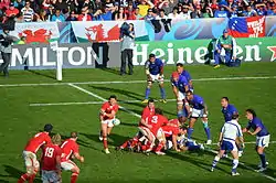 Photographie d'un match de rugby à XV entre le pays de Galles en maillots rouges et les Samoa en maillots bleus