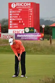 Une golfeuse sur un green avec un putt en main.