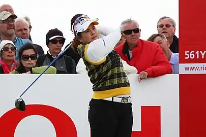La golfeuse passe ses deux mains derrière sa nuque, terminant son geste.