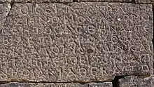 Photographie d'un bloc de pierre gravé d'un texte en grec.