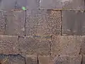 Partie d'un mur de Qasr al Hallabat constitué de blocs de basaltes dont l'un est recouvert d'écritures grecques