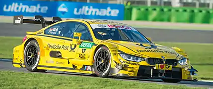 Photographie d'une voiture de tourisme jaune, vue de trois-quarts, sur un circuit.