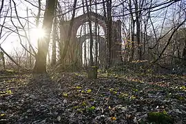 Une borne entre les arbres, la silhouette d'un bâtiment apparaît à l'arrière plan.