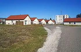 Un groupe de maisons récentes et une petite tour HLM derrière