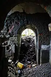 Petite pièce avec des murs en pierre et des ouvertures arrondies.