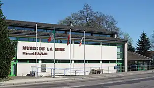 Vue extérieure d'un bâtiment utilisé comme musée et portant l'inscription « Musée de la mine Marcel Maulini » en façade.