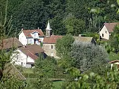 Groupement de maisons autour d'un bâtiment surmonté d'un clocheton en pointe.