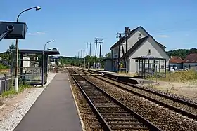 Deux voies ferrées bordée de deux quais et d'un petit bâtiment de gare.