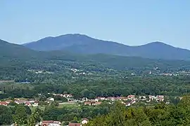 Une montagne arrondie s'élevant au-dessus d'une plaine vallonnée et boisée.