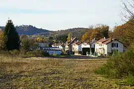 Une route bordée de deux rangées de maisons avec une grande colline en arrière plan.