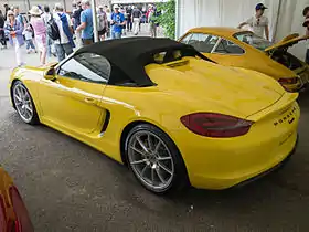 Une Boxster Spyder (981) jaune à l'arrêt, capote fermée, vu de 3/4 arrière.