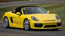 Photo d'un Boxster Spyder (981) jaune, en virage sur un circuit.