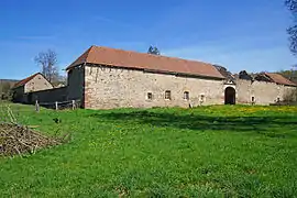 Un porche d'entrée en pierre taille avec toiture en ruine.