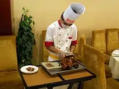 Découpage du canard devant les clients d'un restaurant gastronomique.