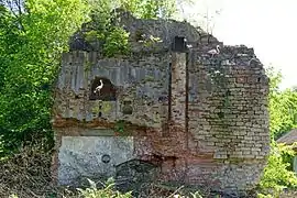 Des ruines de murs formant un massif pyramidal au milieu de la végétation jaunie en hiver.