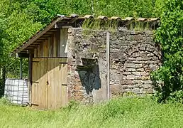 Mur en pierre de taille et en brique servant d'appui à une cabane en bois