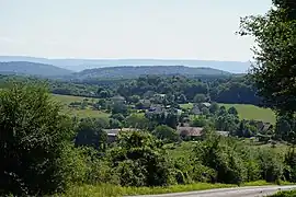 Photo couleur de quelques maisons en contrebas, bordé de collines.