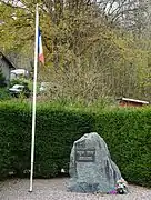 Plaque sur un rocher et mât portant un drapeau français.