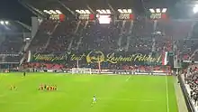 Photo montrant une tribune de stade, barrée d'une grande banderole noire et jaune.