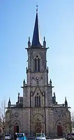 Façade et clocher en flèche d'une église de style néogothique.