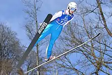 Une sauteuse à ski en train de voler avec les skis en V.