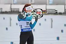 Biathlète, de face, en train de tirer sur sa gauche.