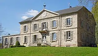 Un manoir de style Napoléon III avec un fronton, un balcon, une terrasse à l'étage et de nombreuses cheminées.