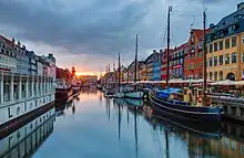 Un canal, bordé d'un quai où des bateaux de style traditionnel touristique ont accosté.