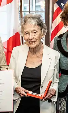 photographie en couleur d'une vieille femme debout tenant une récompense