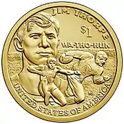 Pièce de monnaie représentant le buste d'un homme jeune à l'arrière-plan, un sauteur en longueur et un joueur de football américain à l'avant-plan et les inscriptions UNITED STATES OF AMERICA, $1, Jim Thorpe et WA-THO-HUK.