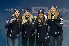 Quatre fondeuses, de face, présentant leur médaille aux photographes.