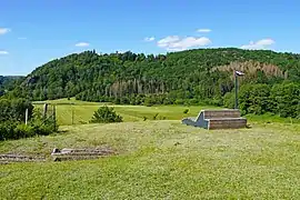 Un banc équipé d'un panneau solaire faisant face un paysage de collines boisées surplombant de prairies.