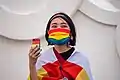 Une personne portant un masque, un serre-tête et un téléphone portable aux couleurs de l'arc-en-ciel LGBT à Taïwan en 2020.