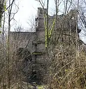 Un grand bâtiment de pierre et de brique entre les arbres.