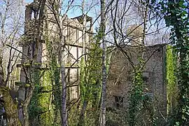 Un grand bâtiment de pierre et de brique entre les arbres.