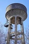 Un réservoir en béton supporté par des piliers eux-mêmes en béton émergeant des arbres.