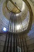 L'intérieur d'un château en béton avec un escalier en colimaçon et un dizaine de conduites métalliques.