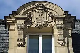 Blason de la ville encadré de volutes sur le fronton au-dessus de la fenêtre centrale du deuxième étage.