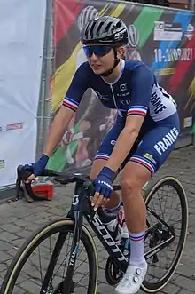 Une coureuse cycliste sur un vélo habillée d'une tenue aux couleurs de l’équipe de France.