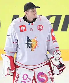 Photographie couleur d’un gardien de hockey, de buste pris de 3/4, portant son casque et regardant vers le haut