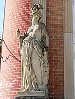 Statue d'une femme en armure. Elle porte un casque, un bouclier et une lance.